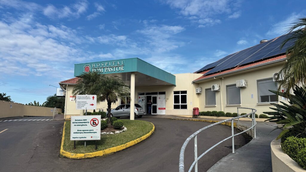 Fachada do Hospital Bom Pastor, em Igrejinha, com letreiro verde na marquise da entrada e painéis solares no telhado.